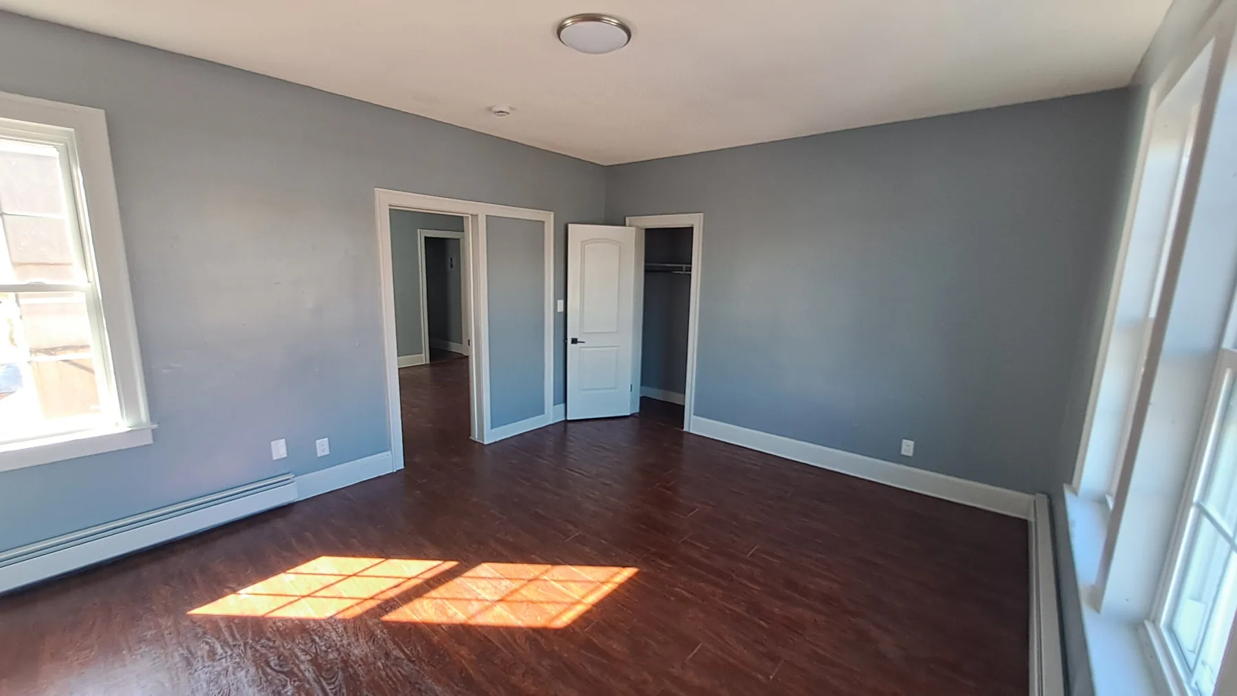 A completed apartment room shows renewed walls, trim, flooring, and a brighter residential interior.