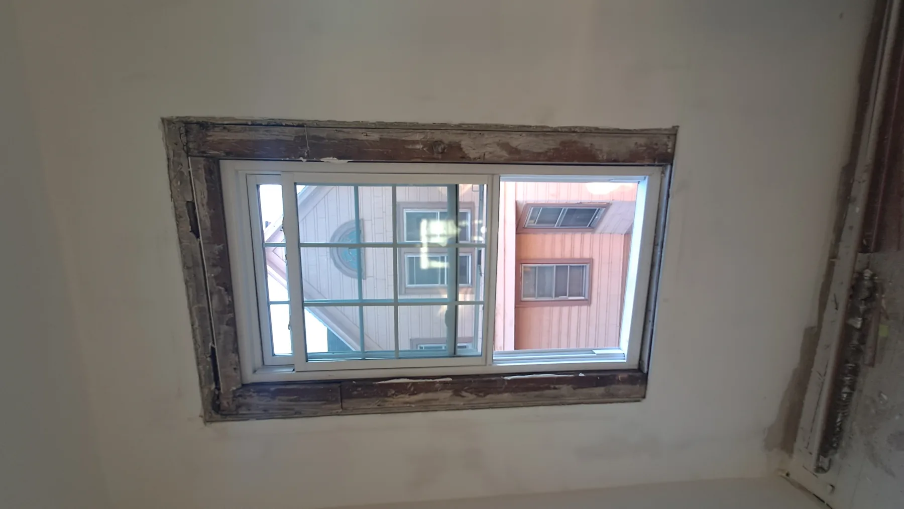 New window installation and unfinished trim document active work inside an apartment.
