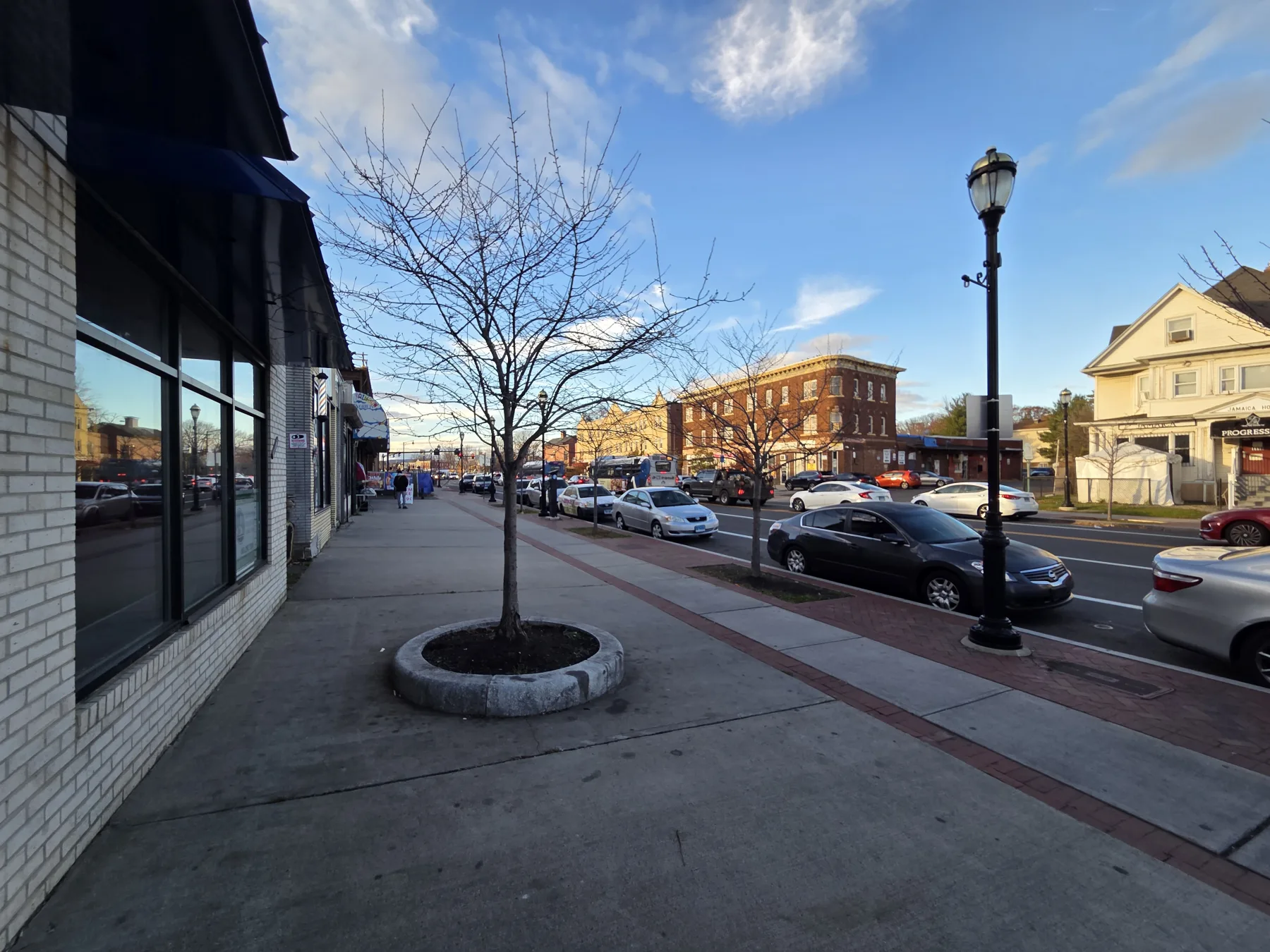 The finished glazing and storefront frame are seen from the rebuilt sidewalk edge looking down Albany Avenue.