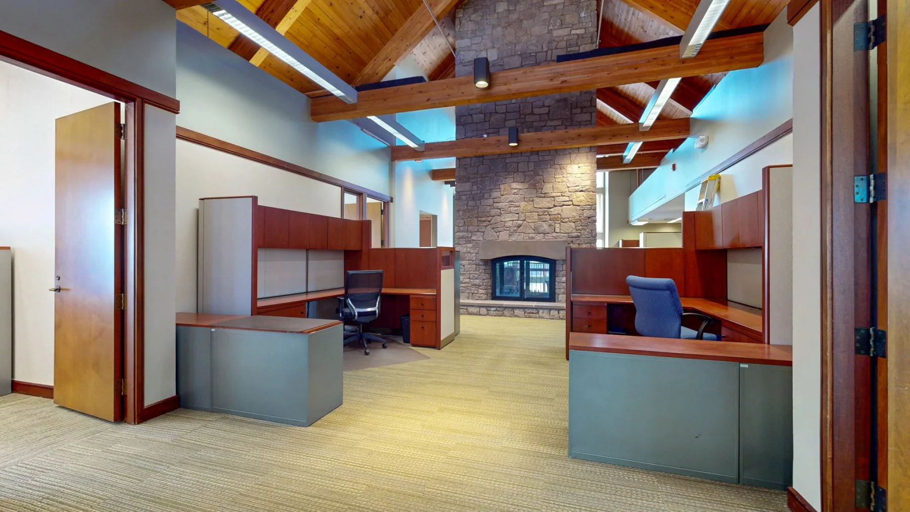 A stone fireplace and timber ceiling give one collaborative workspace a distinctive focal point.