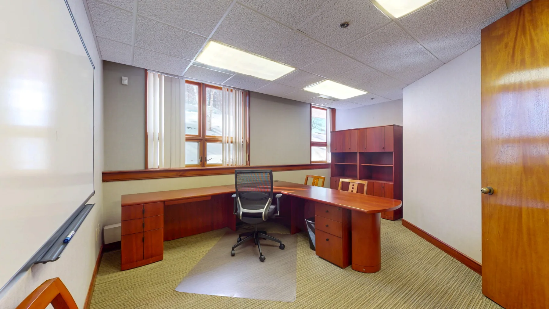 A finished executive office adds built-in storage, a whiteboard wall, and natural light.