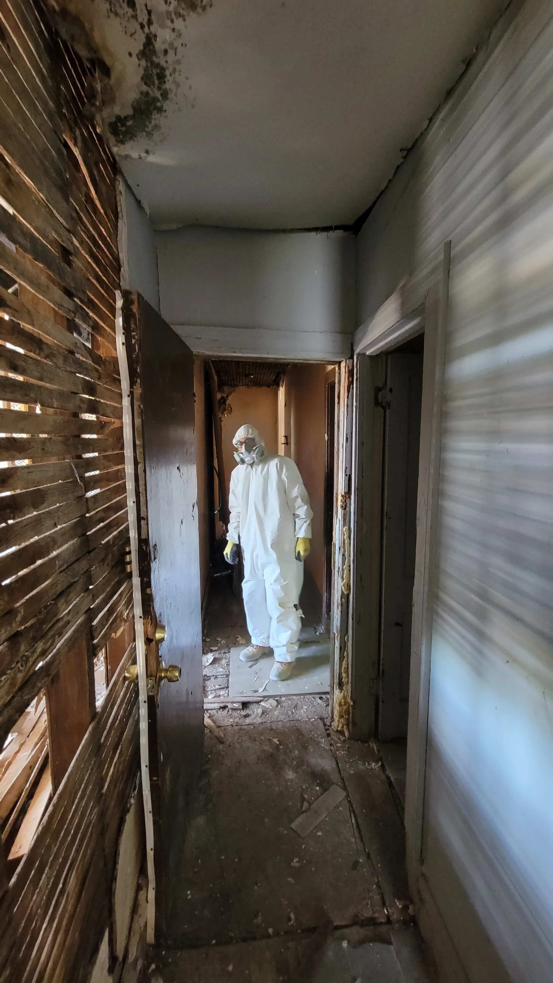 A remediation worker inside the stripped building records the preparation needed before rebuilding could begin.