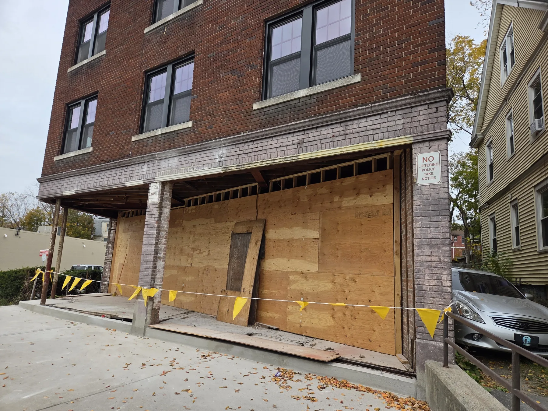 The street-level openings remain boarded while the storefront structure is actively rebuilt.