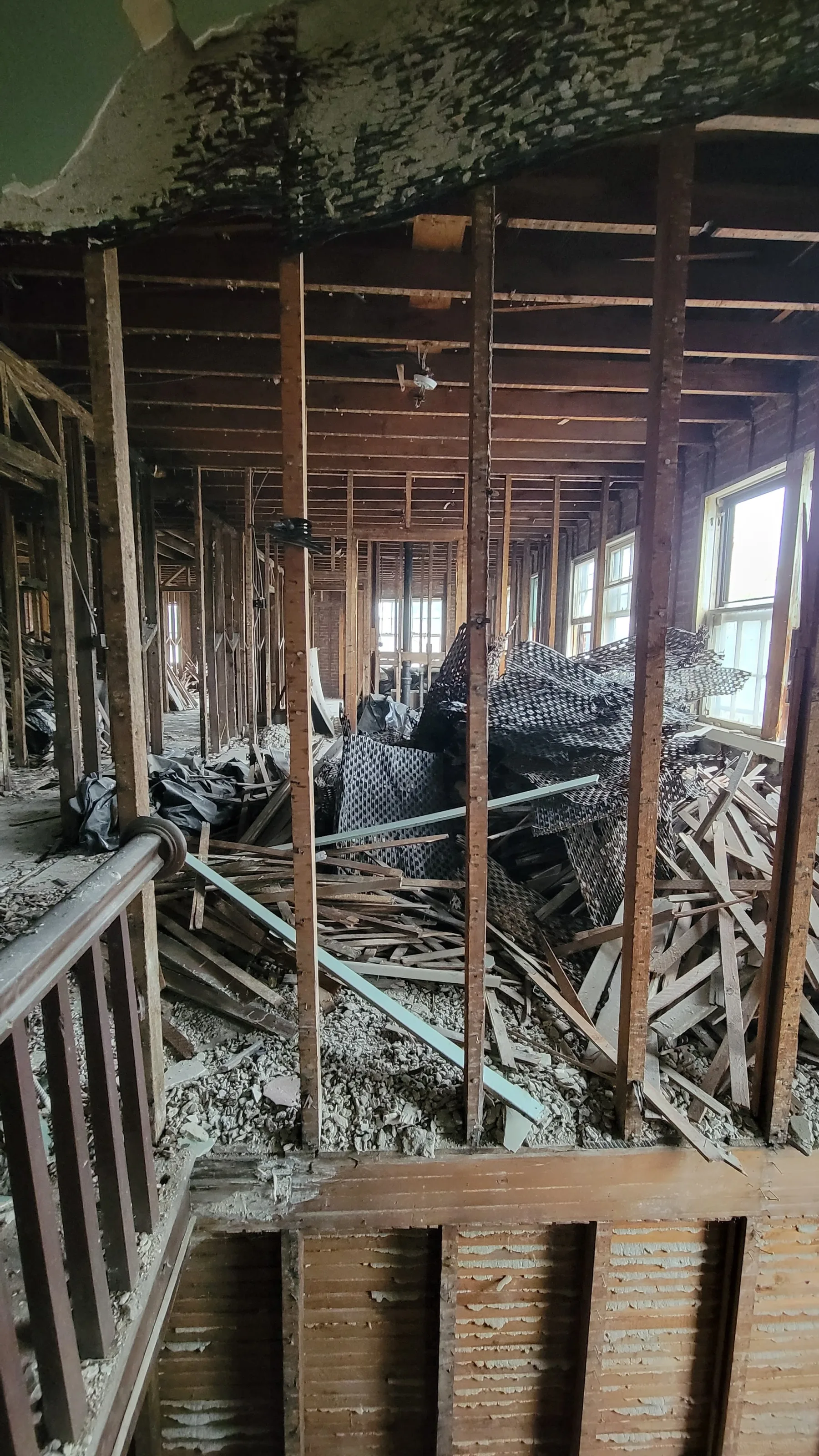 The opened floor reveals the original studs, lath, and accumulated demolition debris before reconstruction.