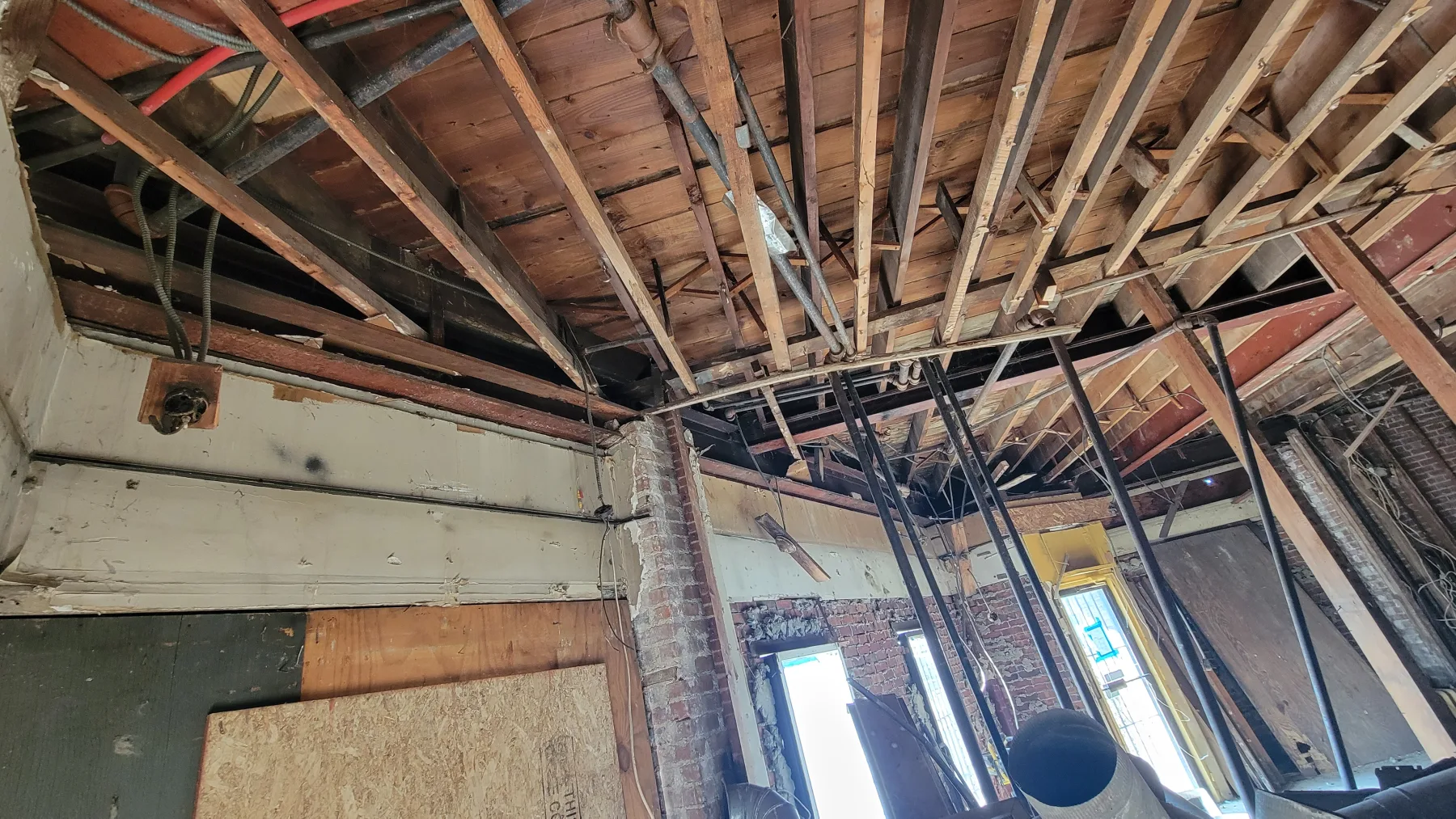 Open ceilings, structural members, piping, and new framing show the rough-in phase before finishes.