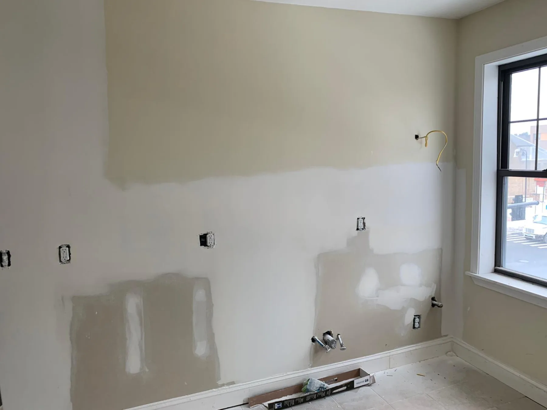 Opened walls and exposed utility connections document the kitchen rough-in stage.