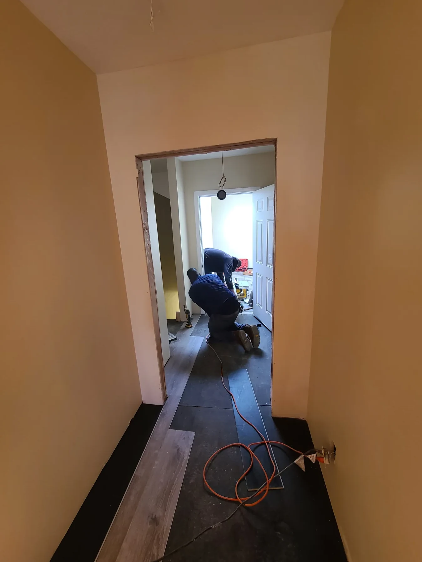 Crews install new flooring through the hall while the doorways and fixtures remain unfinished.