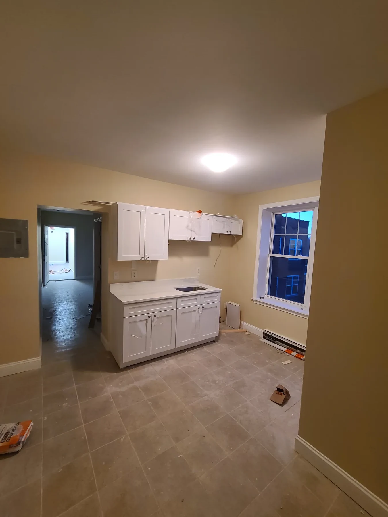 The kitchen advances with finished cabinetry, counters, tile flooring, and final connections still underway.